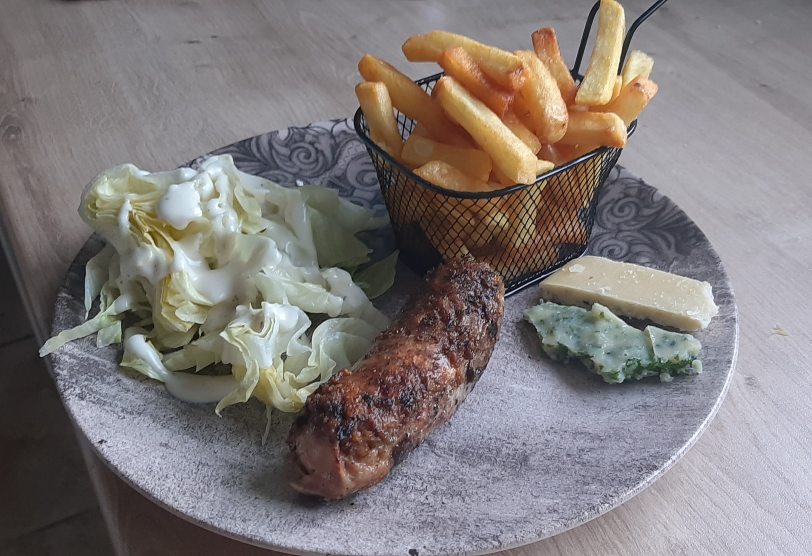 Photo de l'assiette contenant une Andouillette, du beurre composé, de la Salade verte et une paniette de Frites